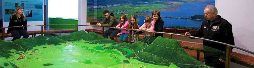 Obiskovalci poslušajo razlago ob maketi Cerkniškega jezera.