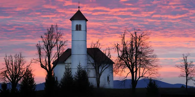 Cerkev svetega Volbenka v Zelšah, fotografirana ob sončnem zahodu, nebo nad njo je okrašeno s prelepimi vijoličastimi odtenki.