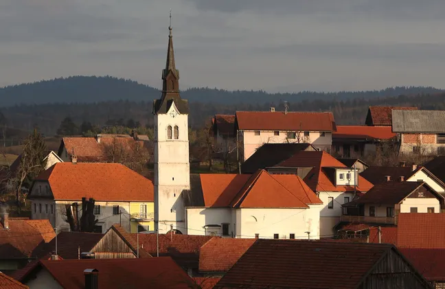 Zvonik Cerkve sv. Martina s temno streho, ki se dviga nad sosednjimi stavbami v Uncu.
