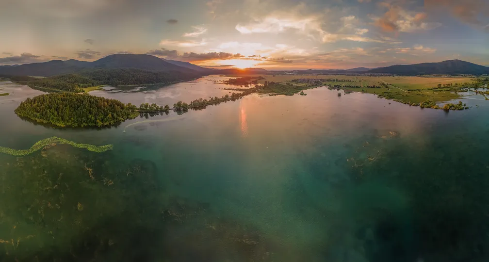 Panoramska slika Cerkniškega jezera iz smeri Javornikov ob sončnem vzhodu.